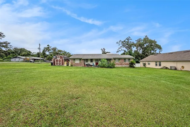 a view of a house with a big yard and large trees