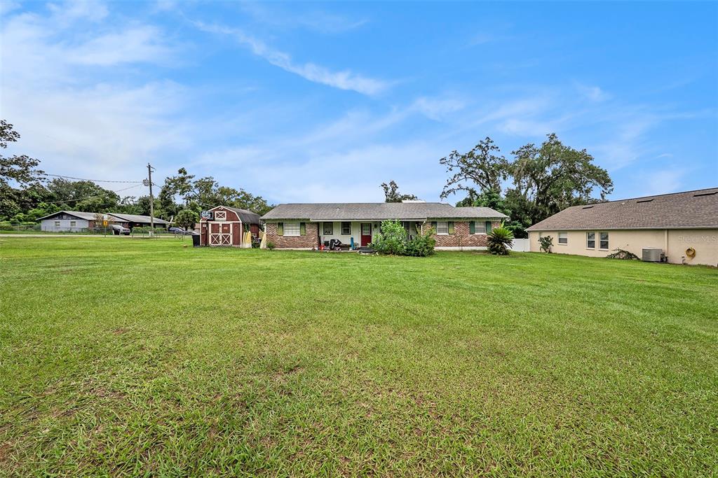 a view of a house with a big yard and large trees