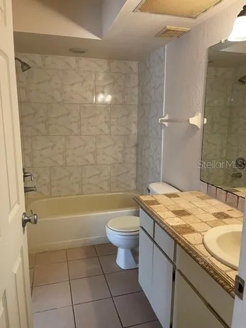 a bathroom with a granite countertop sink a toilet and bathtub