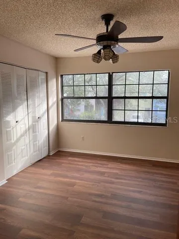 a view of empty room with wooden floor and fan
