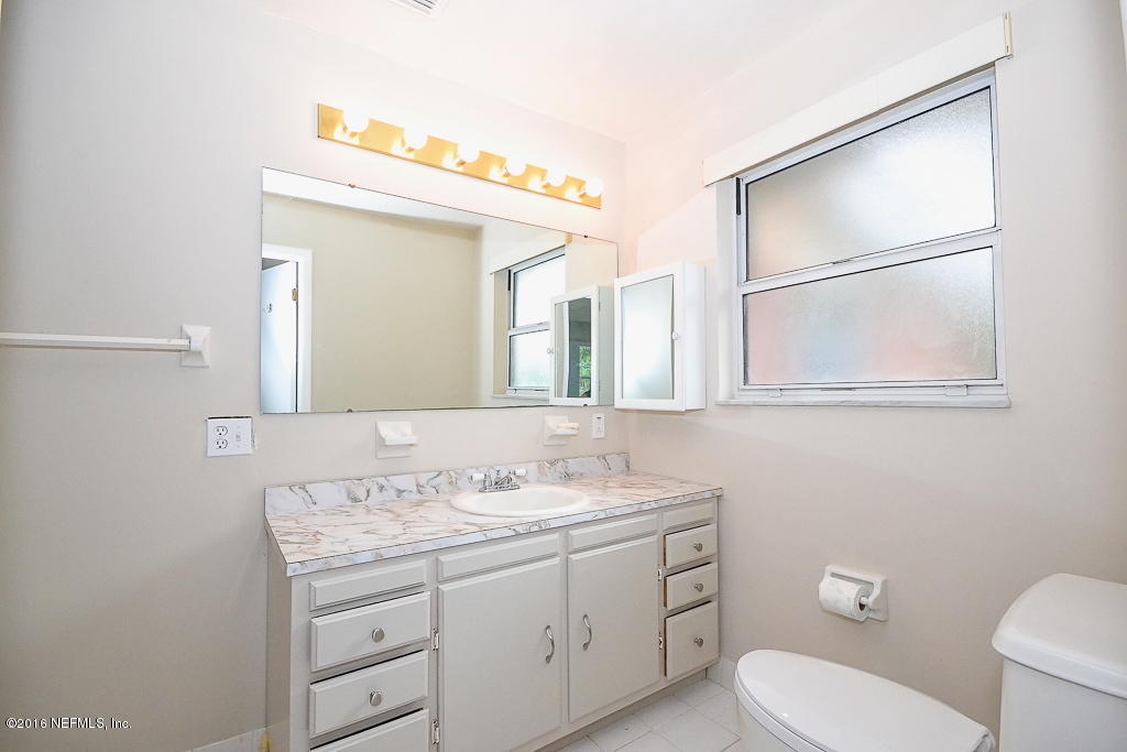 6638 West Fincannon Road Jacksonville, FL 32277 - Photo 17 of 27 a bathroom with a toilet a sink a vanity and mirror