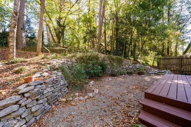 a view of backyard with wooden fence and large trees