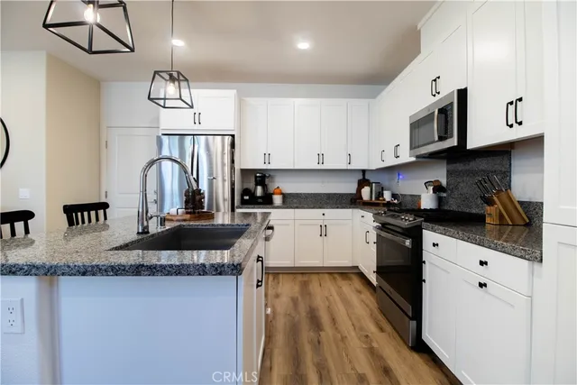 a kitchen with granite countertop a sink a counter space cabinets and stainless steel appliances