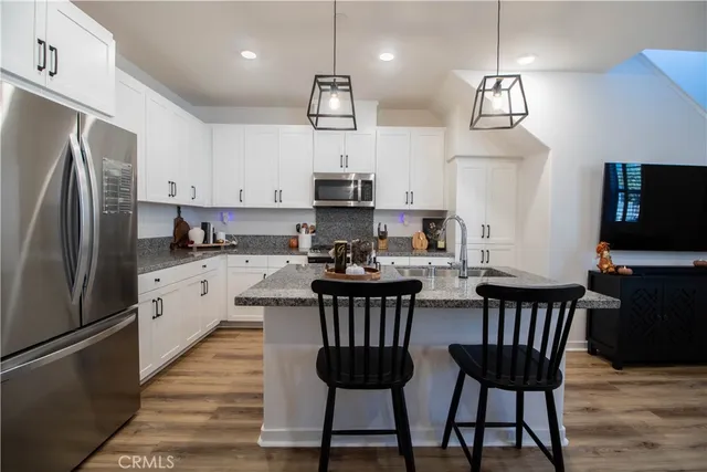 a kitchen with stainless steel appliances a dining table chairs stove and refrigerator