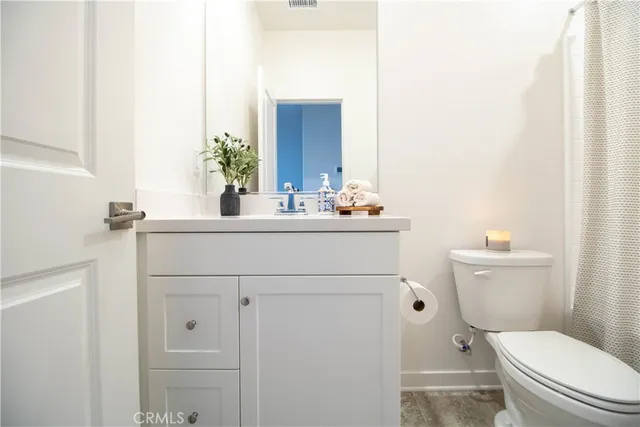 a bathroom with a toilet sink vanity and mirror