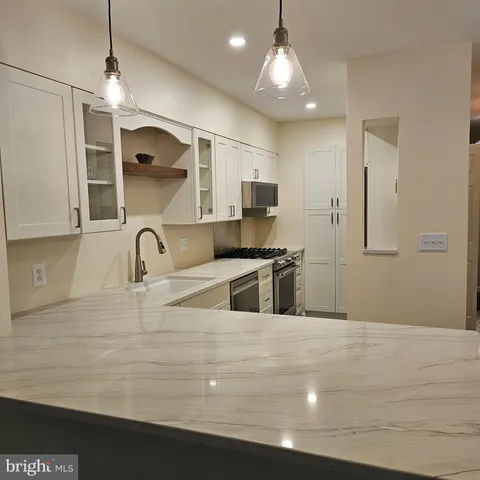 a large kitchen with stainless steel appliances a large counter top a stove and a refrigerator