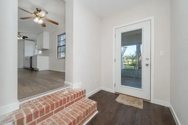 an empty room with windows and ceiling fan