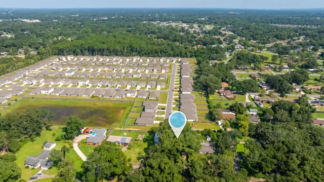 an aerial view of a residential houses with outdoor space and trees