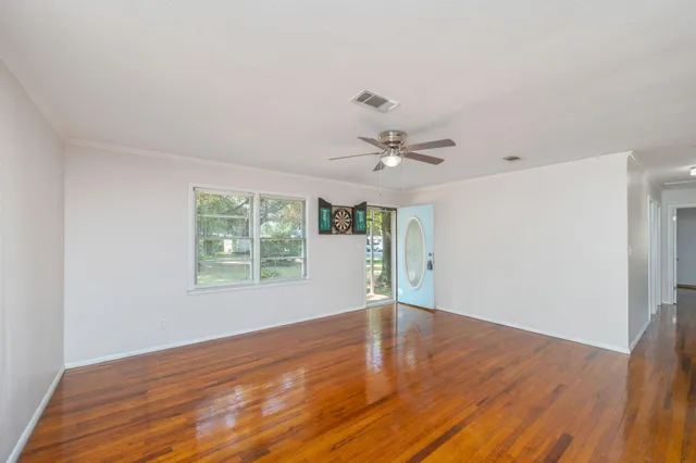 a view of an empty room with wooden floor and a window