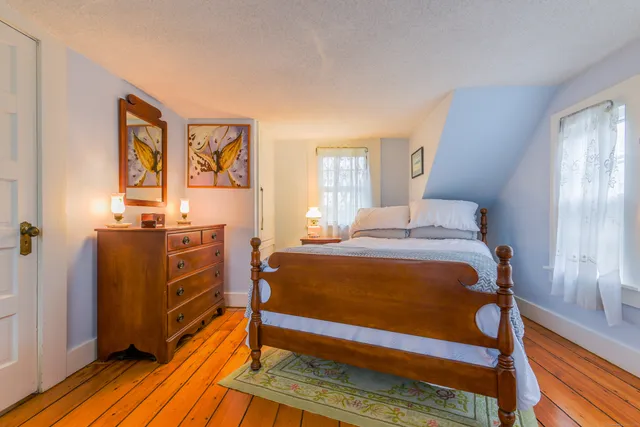 a spacious bedroom with a bed and wooden floor