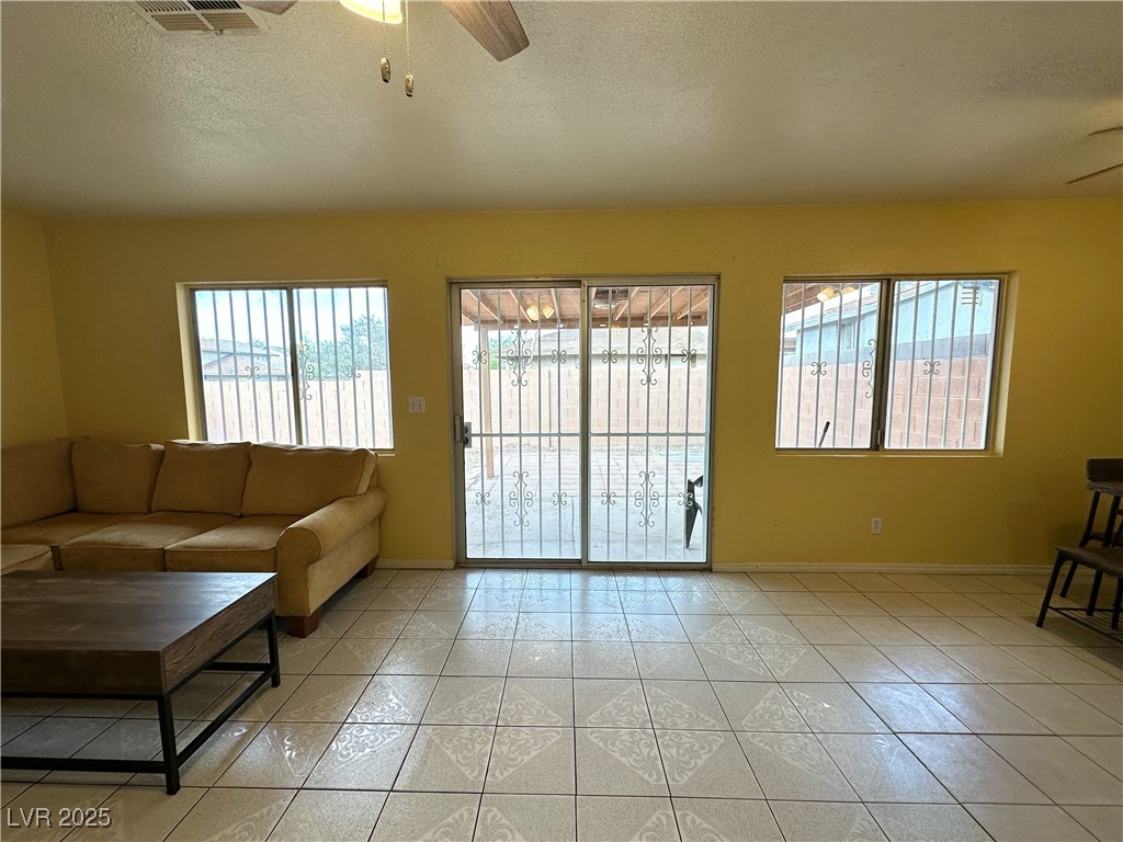 3936 Rive Gauche Street Las Vegas, NV 89115 - Photo 25 of 30 Living room with ceiling fan, plenty of natural light, baseboards, a textured ceiling, and light tile patterned flooring