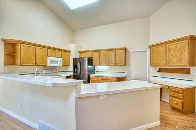 a kitchen with stainless steel appliances granite countertop a sink a stove a refrigerator cabinets and chairs