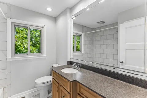 a bathroom with a granite countertop sink and a toilet