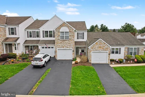 a front view of a house with a garden and trees