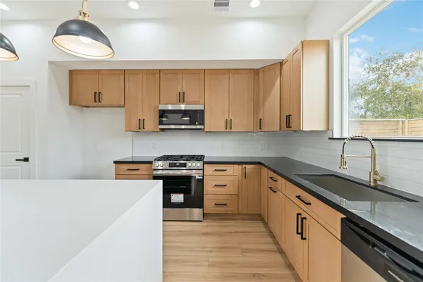 a kitchen with stainless steel appliances granite countertop a sink a stove and a refrigerator