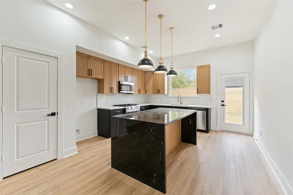a large kitchen with a sink and dishwasher a stove top oven with wooden floor