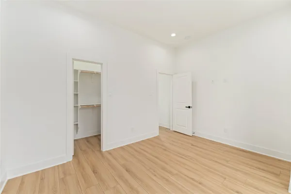 a view of an empty room with wooden floor and closet