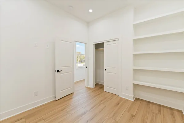 a view of an empty room with wooden floor and closet