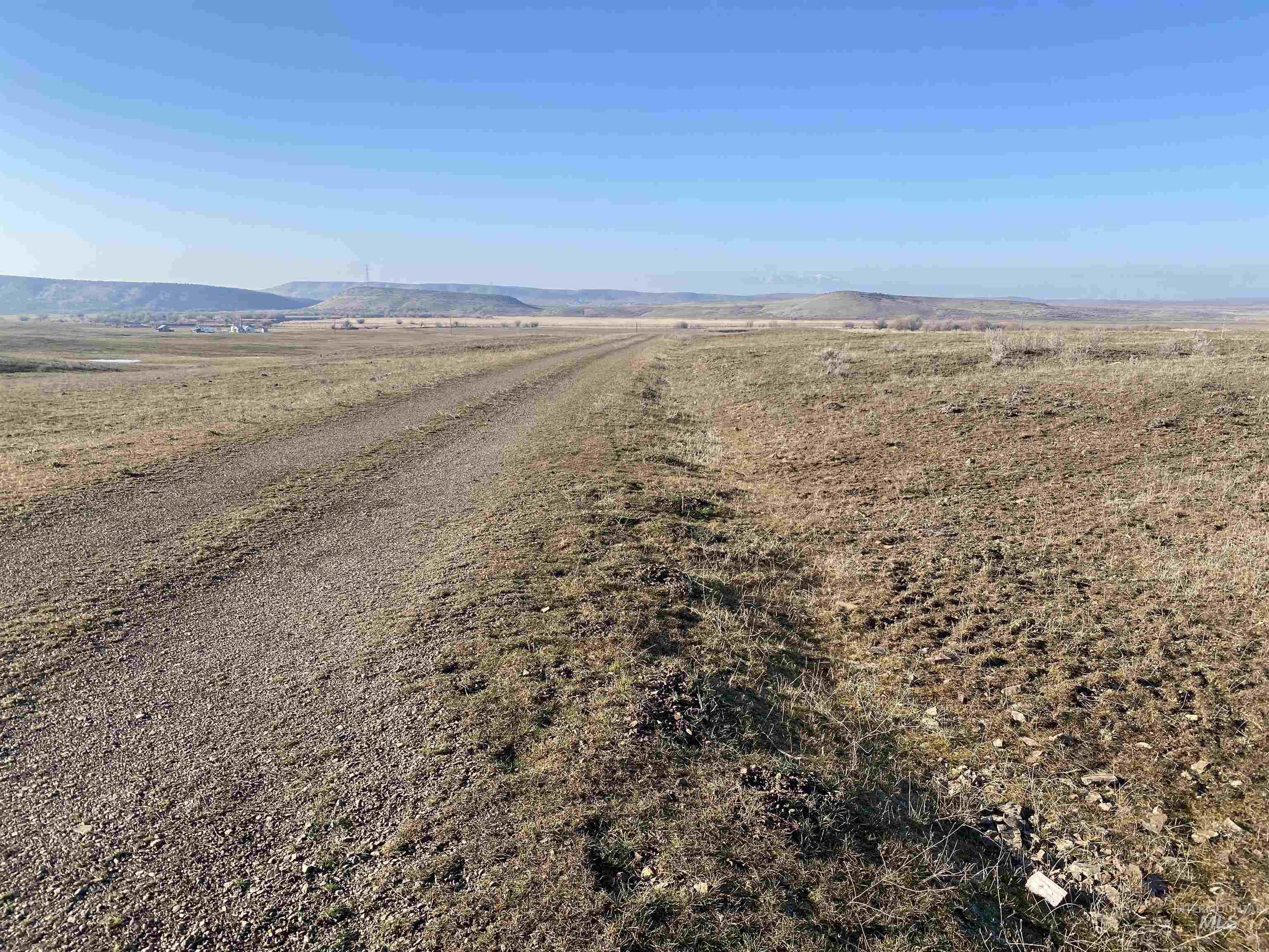 View of dirt / gravel road featuring a mountain view and a view of countryside