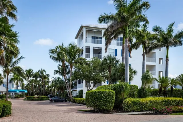 front view of house with a yard and palm trees