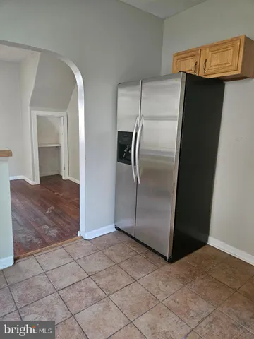a view of a refrigerator in kitchen and an empty room