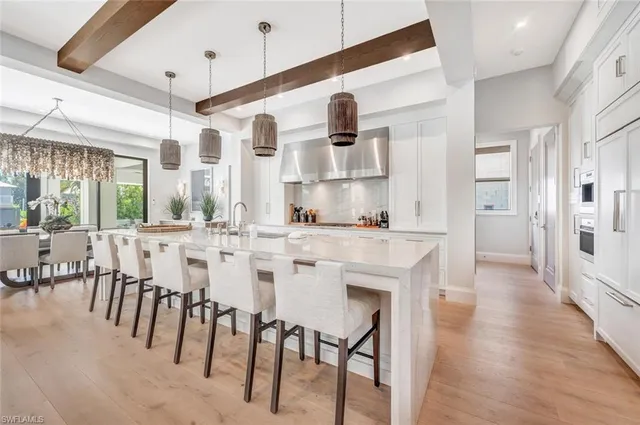 a kitchen with stainless steel appliances kitchen island granite countertop a table chairs sink and cabinets