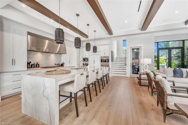 a kitchen with stainless steel appliances granite countertop a stove a refrigerator a dining table and chairs with wooden floor