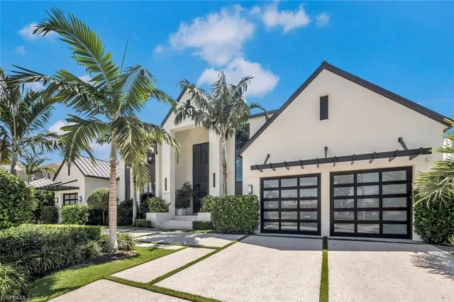 a view of a white house with a yard and potted plants