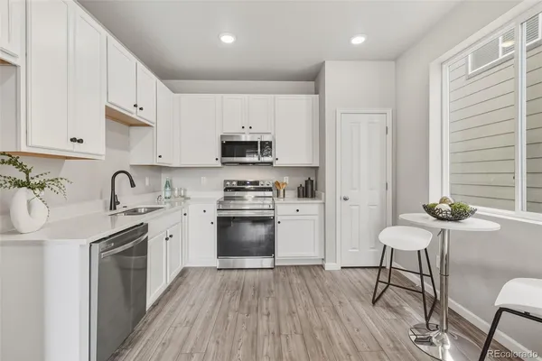 a kitchen with stainless steel appliances white cabinets a sink a stove a refrigerator and a microwave