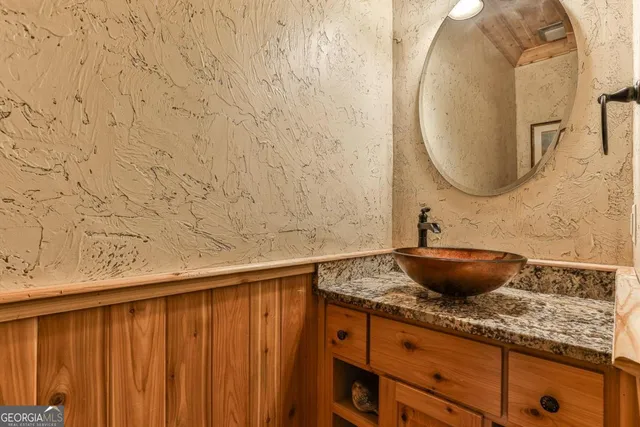 a bathroom with a granite countertop sink a mirror and shower