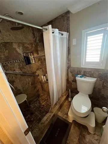 a white toilet sitting next to a bathroom sink and a shower