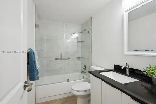 a bathroom with a granite countertop sink toilet and shower