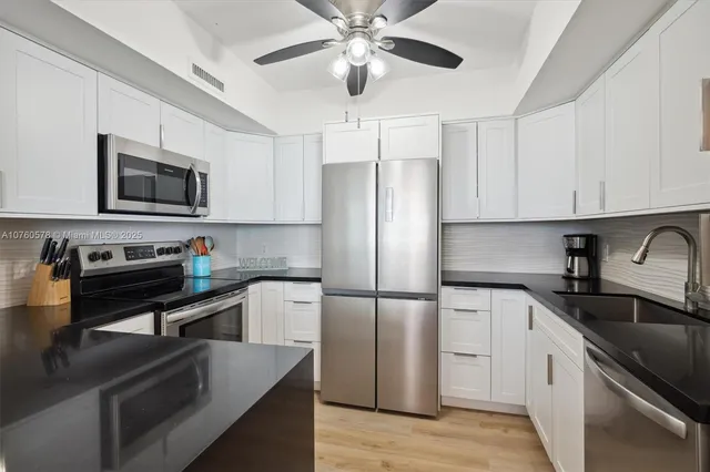 a kitchen with stainless steel appliances granite countertop a refrigerator a stove top oven a sink and dishwasher