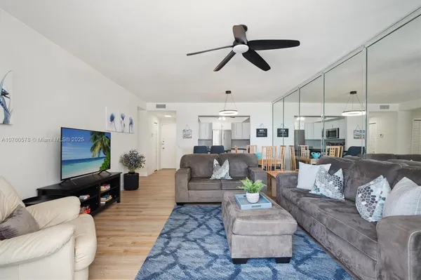 a living room with furniture kitchen view and a wooden floor