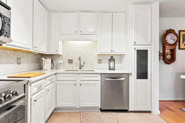 a kitchen with stainless steel appliances granite countertop white cabinets and sink