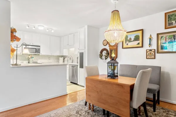 a dining room with kitchen island stainless steel appliances furniture a chandelier and wooden floor