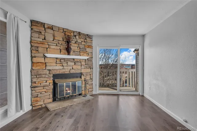 a view of an empty room with wooden floor fireplace and a window