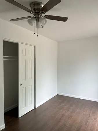 an empty room with a ceiling fan and wooden floor