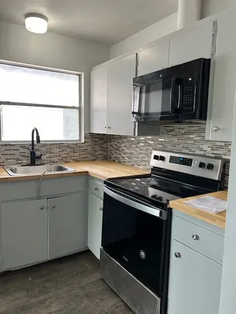 a kitchen with granite countertop a stove top oven cabinetry a sink and a window