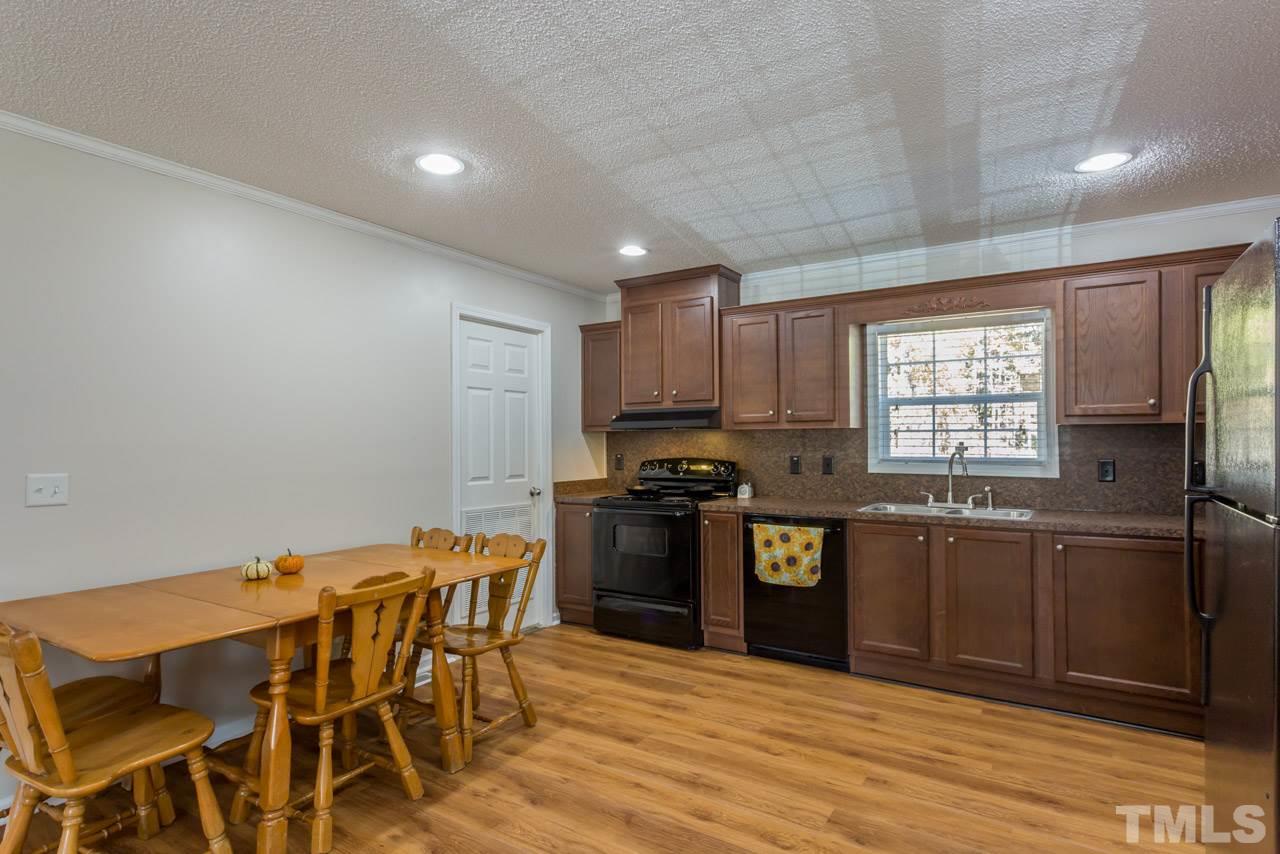 1001 Altice Drive Raleigh, NC 27603 - Photo 15 of 24 a kitchen with stainless steel appliances granite countertop a stove top oven a sink dishwasher a dining table and chairs with wooden floor