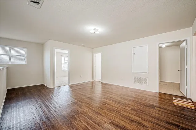 an empty room with wooden floor and windows