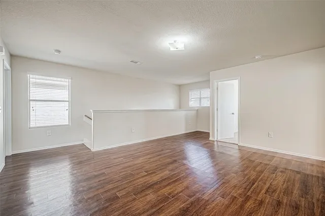 an empty room with wooden floor cabinet and windows