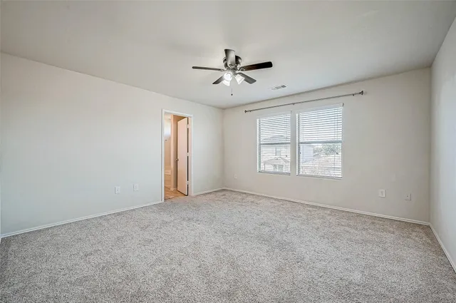 an empty room with windows and fan