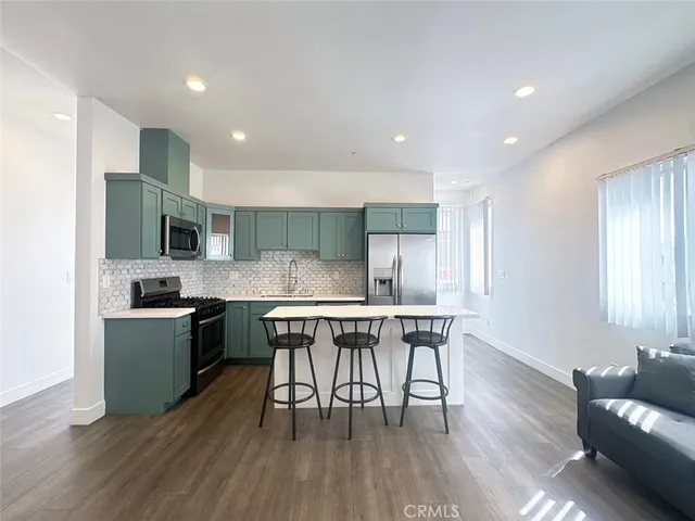 a kitchen with stainless steel appliances a dining table chairs stove microwave and cabinets