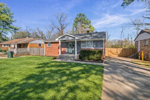 a front view of a house with a garden and trees