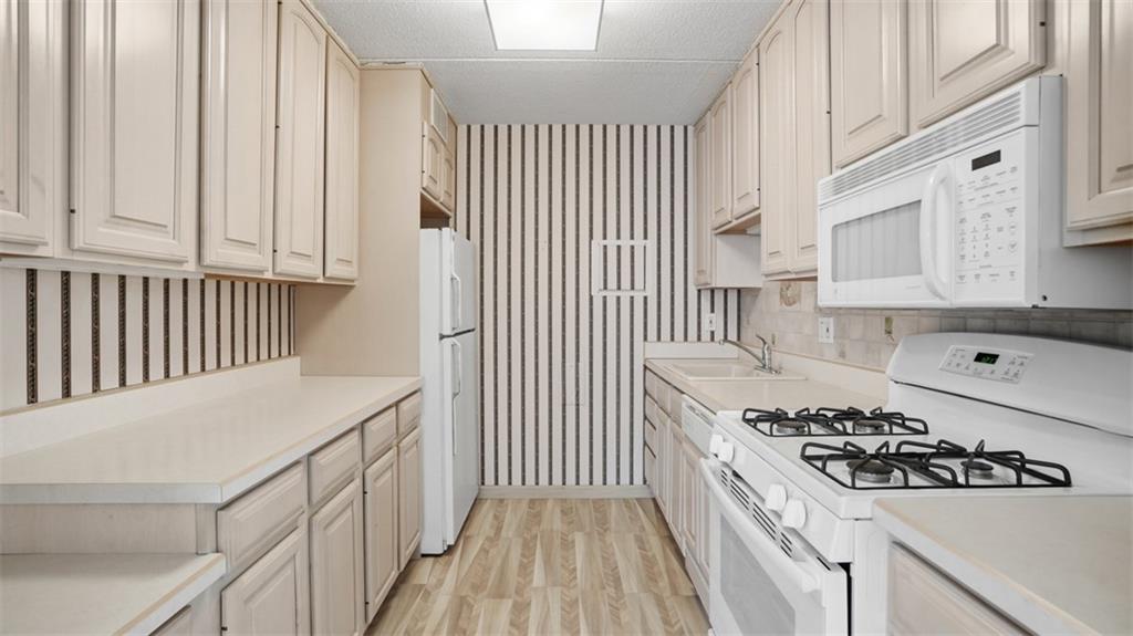 1160 Bower Hill Road, Unit 716A Mt. Lebanon, PA 15243 - Photo 19 of 36 Galley kitchen with SCHROCK HANDCRAFTED CABINETRY AND WHITE APPLIANCES.