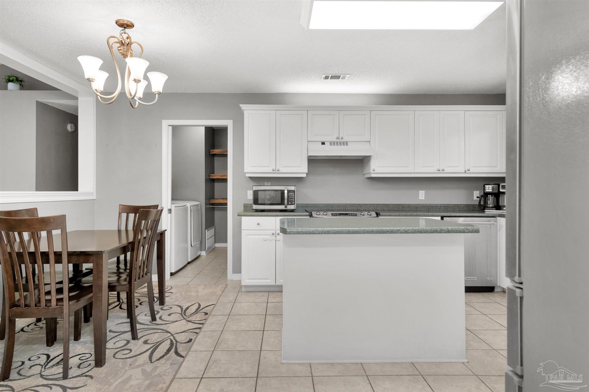 2702 Beacon Court Navarre, FL 32566 - Photo 9 of 29 a kitchen with a stove a table and chairs in it