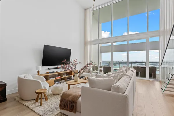 a living room with furniture a flat screen tv and a floor to ceiling window