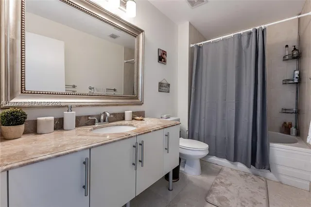 a bathroom with a granite countertop toilet sink and mirror