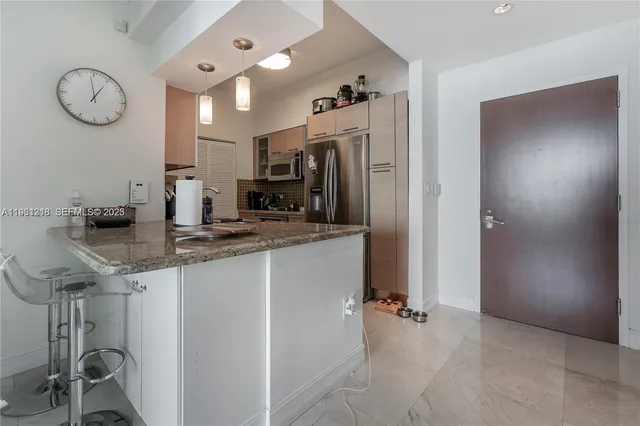 a metallic refrigerator freezer and a stove sitting inside of a kitchen